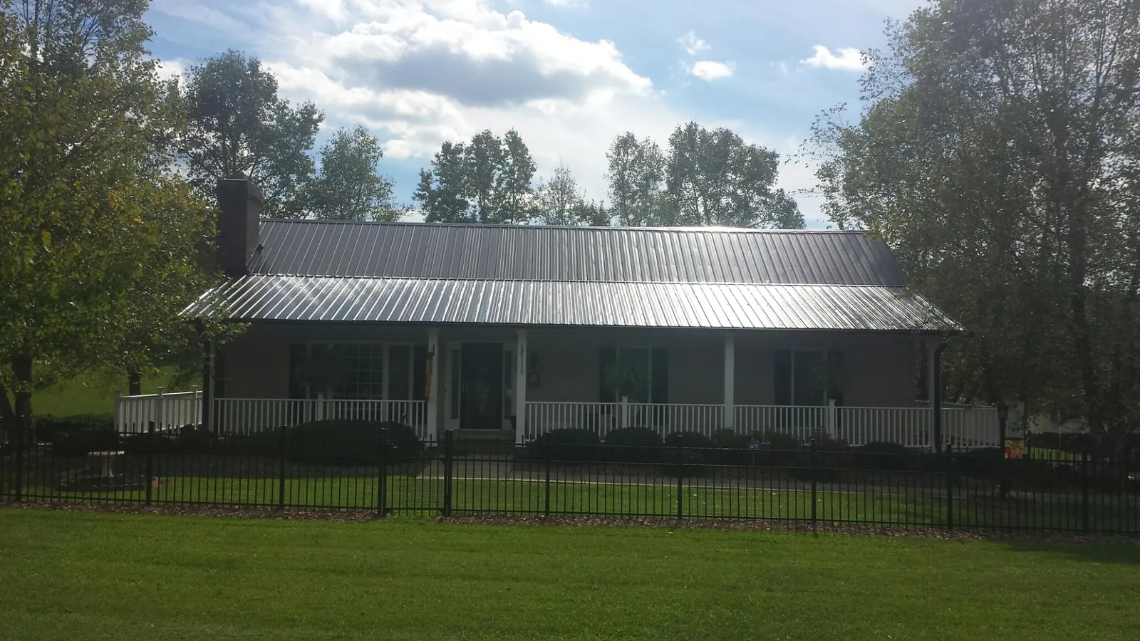 Gray metal roof on a brick ranch with a full width front porch — Gutter Guard Installation work by our crew in Ocala