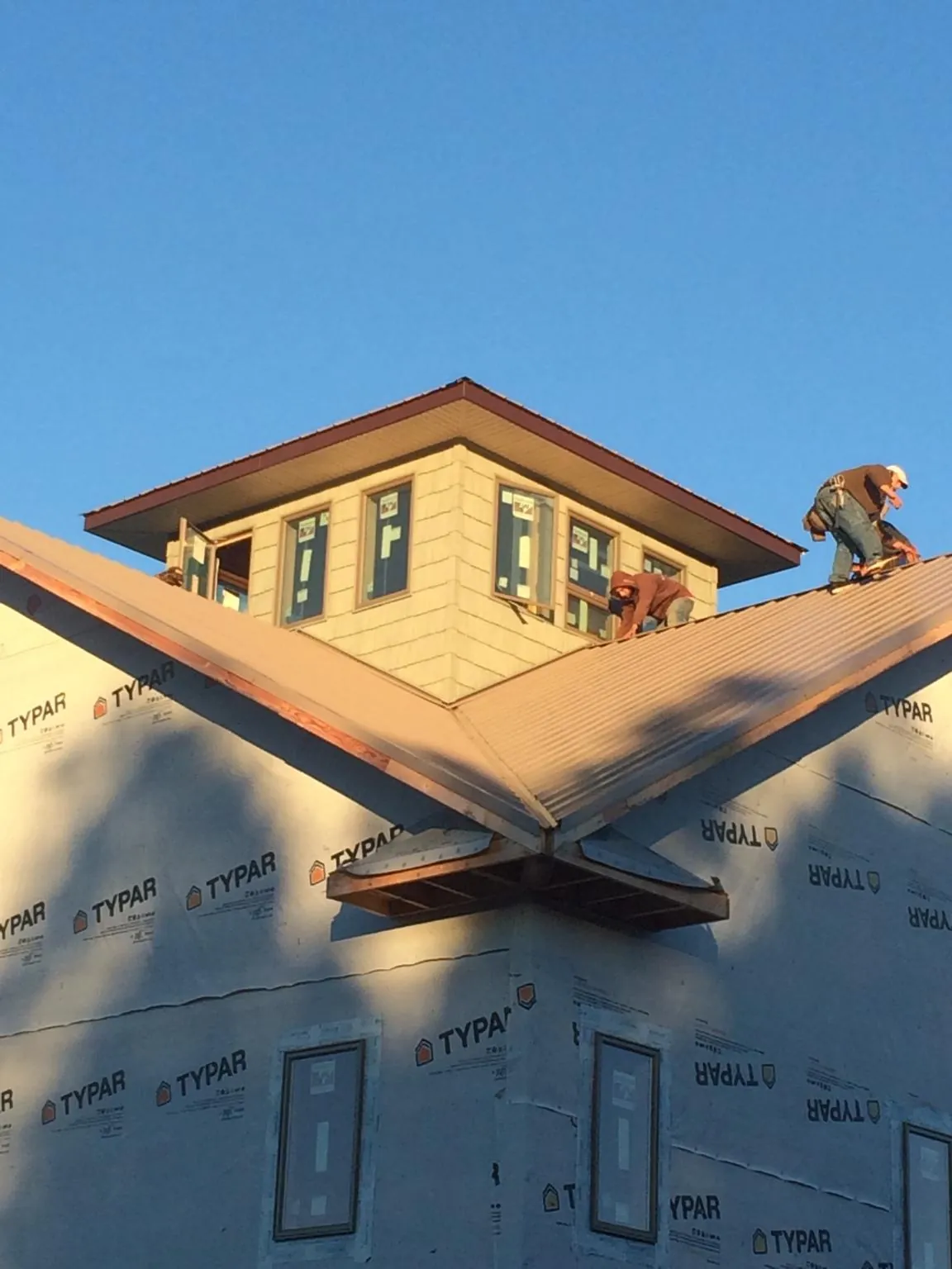 Roofers working around a rooftop cupola on a new metal roof at sunset — Roof Waterproofing in Ocala by Roofing Brothers